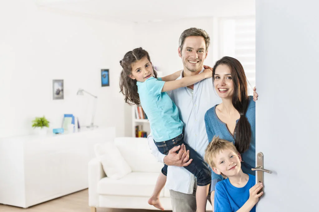 Family standing at front door to invite people at home